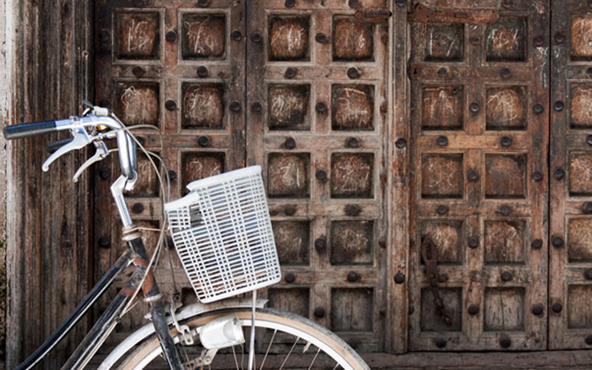 A large double wooden door in Stone Town with a white bicycle in the front