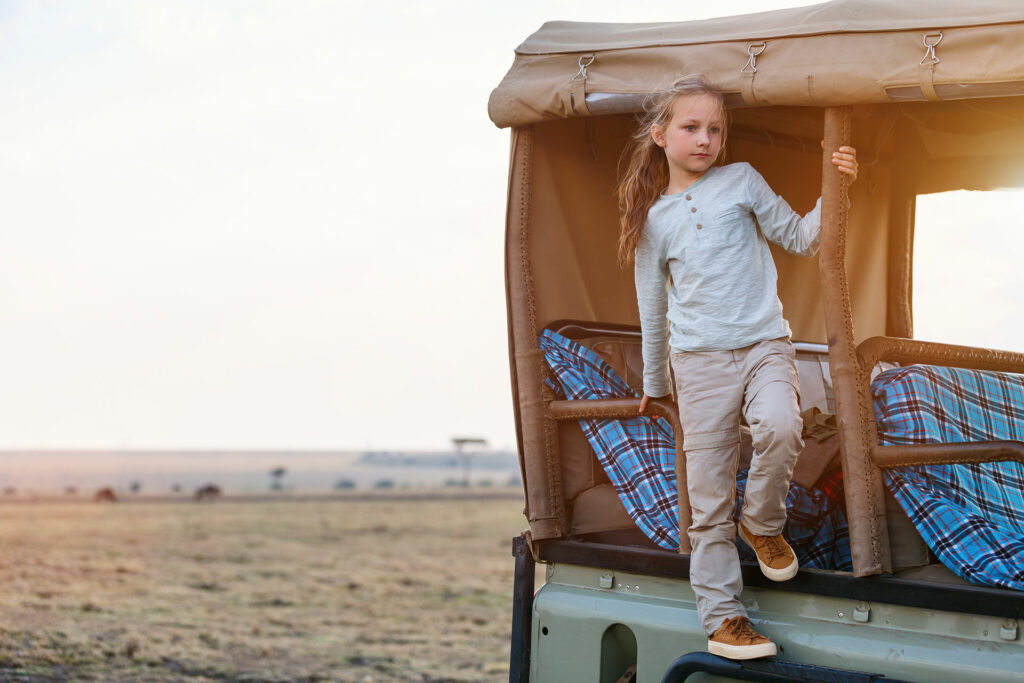 A girl on the side of a game drive vehicle for sustainable safaris