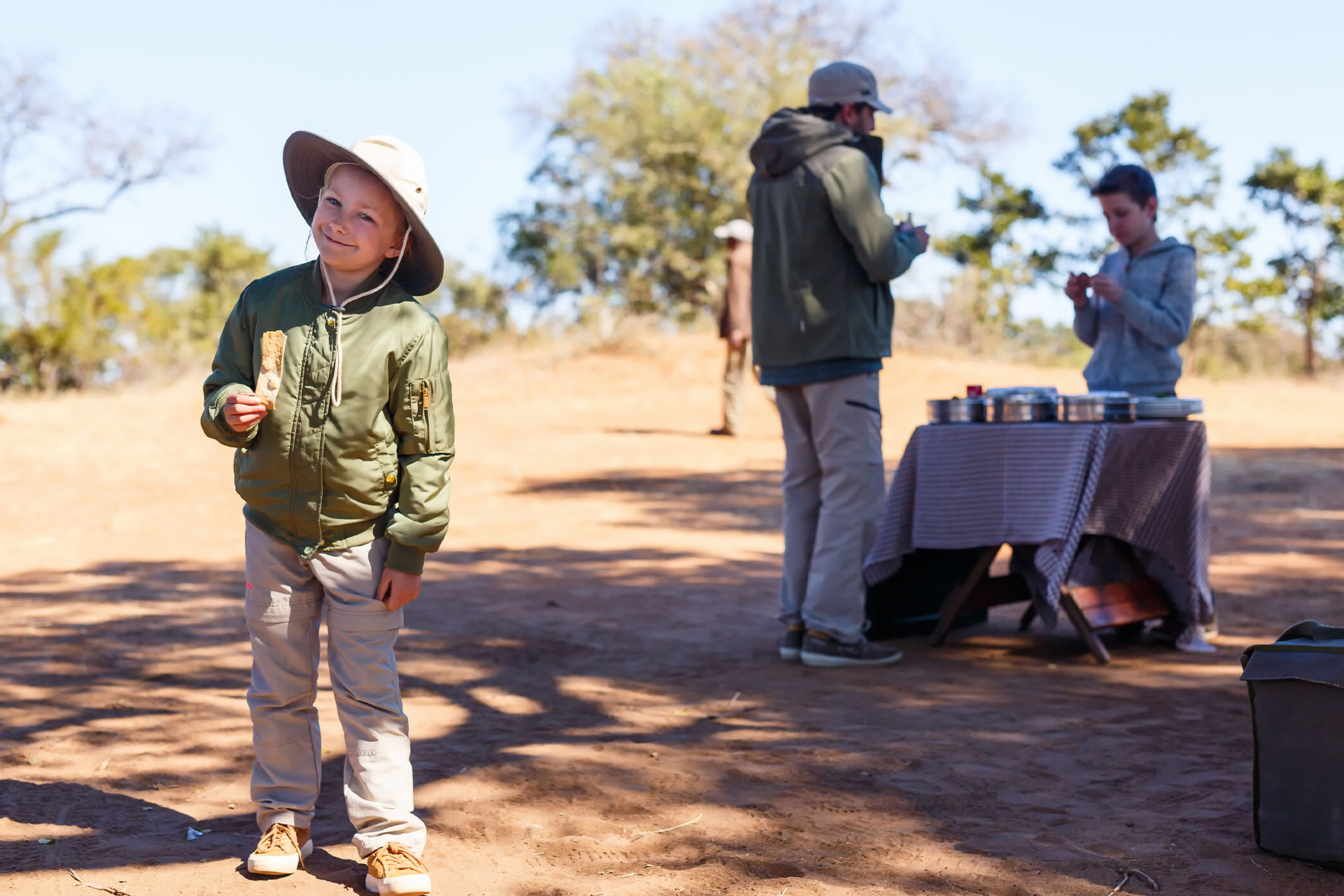 A young boy with a ranger in the background on one of the Grand Africa Safaris sustainable safaris